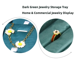 Detail view of dark green velvet jewelry tray showing golden daisy bracelet and pearl ring