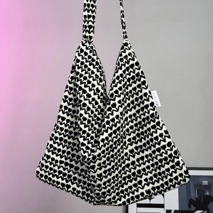 Close-up of black and white tulip pattern on thick knitted tote bag with woven brand label