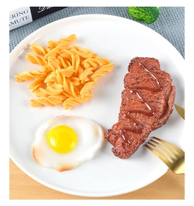 Realistische kunstmatige biefstukset met gebakken ei en spiraalvormige pasta op wit bord