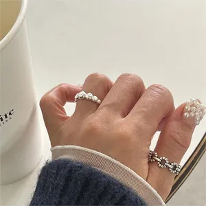 Close-up of irregular textured silver wide band and beaded chain ring set on a finger