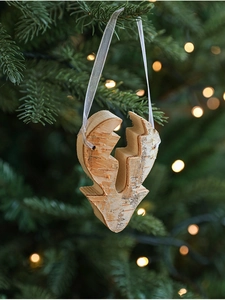 Detail of a natural wood Christmas tree ornament with bark texture hanging on pine branch