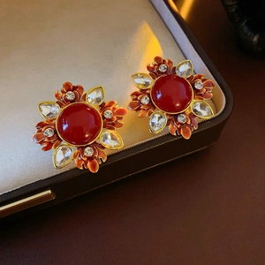 Detail of vintage gold earrings with red round stone and maple leaf crystal accents
