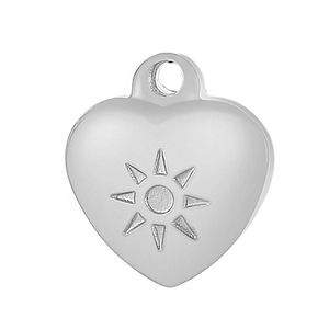 Macro view of silver heart pendant featuring sun motif and polished metal finish