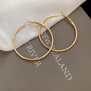 Macro detail of gold hoop earrings with leverback closure on elegant silk fabric