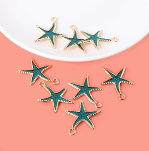 Detailed view of eight green enamel starfish pendants with golden metal edges for jewelry