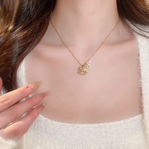 Detail of gold-plated lucky horse pendant necklace on a model with white knitwear