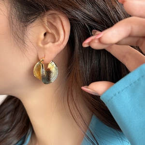 Retro golden shell-textured hoop earrings with a brushed vertical stripe finish on a model