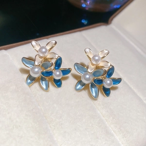 Macro shot of 18K gold plated flower stud earrings with enamel petals and pearls