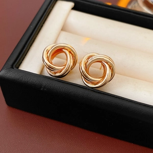 Gros plan de boucles d'oreilles spirales dorées sur un coussin en suédine dans un coffret noir