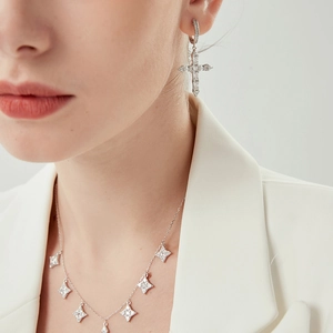 Detail of silver cross pendant earring and star necklace with shimmering zircons