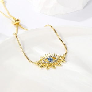 Detail of gold evil eye bracelet with blue center stone and adjustable slider clasp