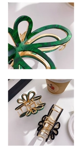 Close-up of acetic acid butterfly hair claws with gold-rimmed marble and black finishes