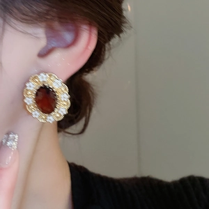 Detail of vintage oval earring with amber gem and gold floral frame on a female model
