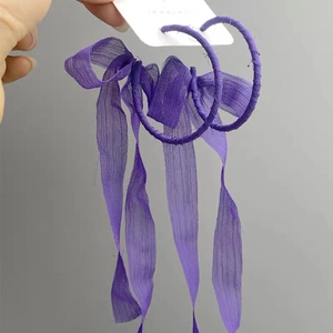 Detail showing oversized purple chiffon ribbon wrapped hoop earrings with long tassels