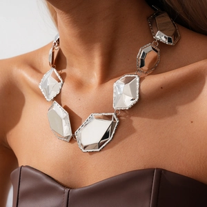 Close-up of chunky silver geometric mirror plates on a heavy industrial style necklace