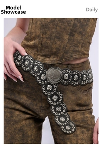 Close-up of black punk waist belt with silver eyelets and vintage embossed metal medallions