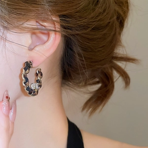 Détail de créoles en C avec tissu léopard, chaîne dorée et pierre en zircone brillante
