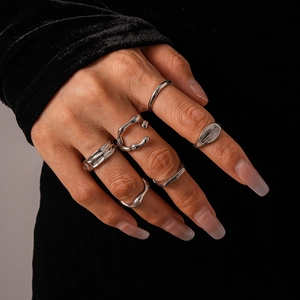 Detailed view of silver irregular geometric rings set on hand with black velvet backdrop