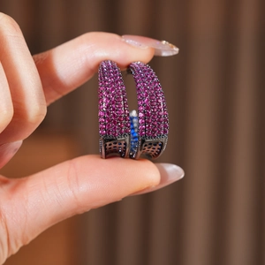 Close-up of vintage black C-shaped earrings with micro-paved magenta zircon stones