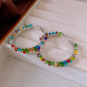 Macro shot of silver hoop earrings featuring colorful faceted crystal beads in a soft gift box