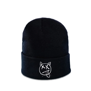 Dettaglio di un berretto nero in maglia con logo gatto bianco con occhi a X e lingua fuori