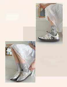 Detail of grey calf-high socks with white cross-lace design and silver ballet-style sneakers