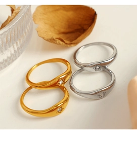 Detail view of gold and silver oval star rings with zircon inlay on a beige surface