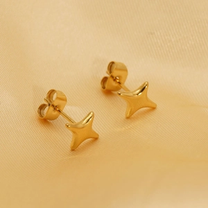 Detailed macro view of golden star-shaped stud earrings on a luxurious silk background