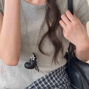 Detail of long sweater necklace featuring leather heart, silver star, and key pendants