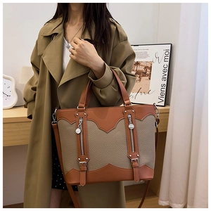 Detail view of brown and taupe leather tote bag with silver hardware and adjustable strap