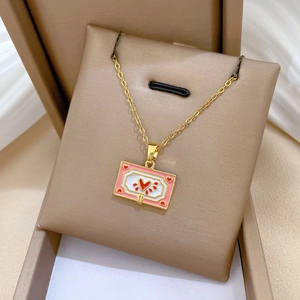 Detailed macro view of a golden heart necklace with pink frame and red enamel center