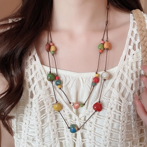 Dettaglio collana a doppio strato con perle colorate in ceramica e cordino marrone