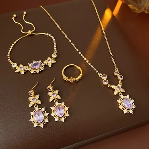 Flat lay of vintage gold jewelry set with purple gemstones and zircon flower accents