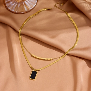 Double-layer gold stainless steel necklace with black rectangular pendant on silk fabric