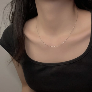 Detailed close-up of a minimalist silver stainless steel chain necklace on a model