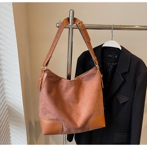 Detail of vintage brown suede tote bag with adjustable strap on a black blazer