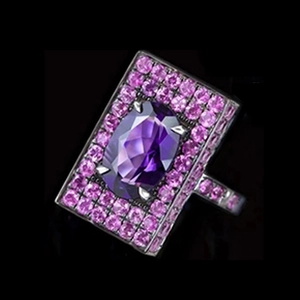 Macro shot of oval purple gemstone with pink side diamonds on silver band