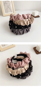 Close-up of pleated satin headbands in multiple colors with elegant rhinestone details