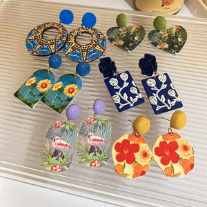 Artistic French sunflower and flamingo earrings displayed on a striped glass tray