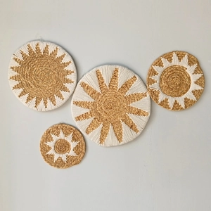 Detail of four handmade straw wall hanging plates with white bohemian embroidery patterns