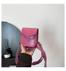Détail de la texture en cuir gaufré crocodile rose sur un mini sac banane