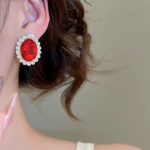 Macro shot of vintage style gold stud earring with large red oval gem and white zircons