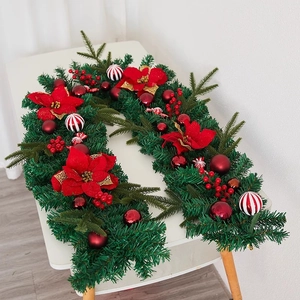 Green Christmas garland with red poinsettia flowers, berries and striped ornaments