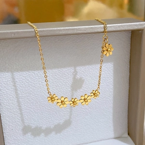 Detailed close-up of six gold flower charms on a minimalist titanium steel necklace