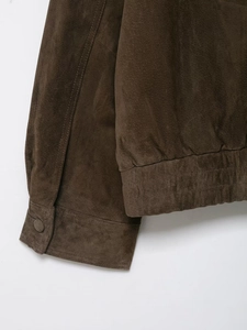 Gros plan sur la texture en daim marron foncé et l'ourlet élastique de la veste pour femme