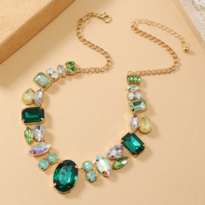 Detail view of bold gold necklace with deep green, light green and iridescent crystals
