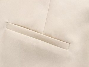 Close-up detail of a tailored welt pocket on beige slim-fit trousers with fine fabric
