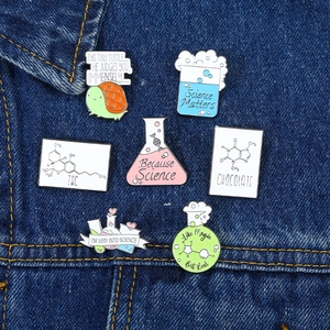 Wissenschafts-Pin-Set mit Laborflaschen und Chemie-Zitaten auf blauem Denim-Stoff