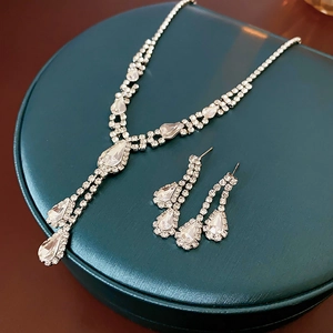 Macro view of teardrop rhinestone necklace and earrings set on green jewelry box