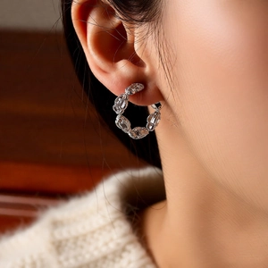 Détail de la texture de chaîne tressée sur boucles d'oreilles portées par un mannequin
